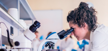 Person looking through microscope