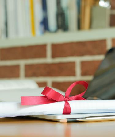 close up bachelor's degree certificate on laptop with book in the library for online learning graduation concept.jpeg