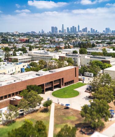 aerial drone perspective of lacc cinema & tv department building in foreground with downtown los angeles skyline in background