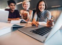 Group of sitting students looking at a laptop 