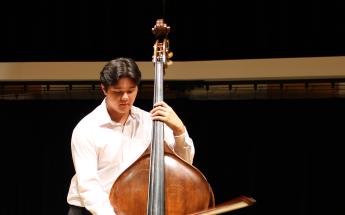 A student plays an upright bass with a bow in the Alpert Recital Hall.