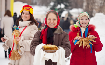Three Russian women smiling and holding traditional cakes