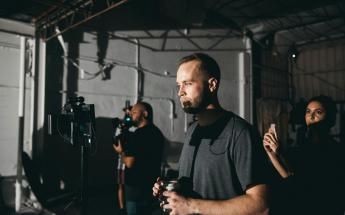 film director with cup of coffee looking at a directors monitor