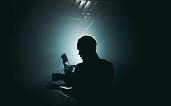 silhouette of a filmmaker with a cinema camera with a blueish light blooming around them