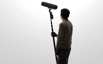 on set sound boom pole operator backlit by large soft light