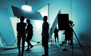 film crew silhouetted on a sound stage with multiple white backdrops