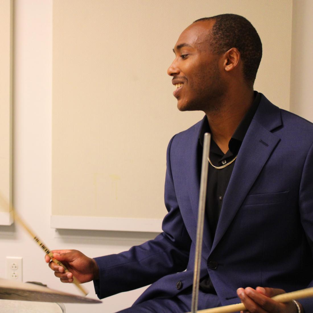 A student plays drum kit in an HAMC practice room.