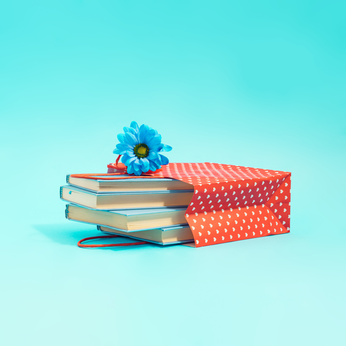 Aesthetic composition of pastel blue books with fresh flower in a red shopping bag and white heart-shaped dots..png