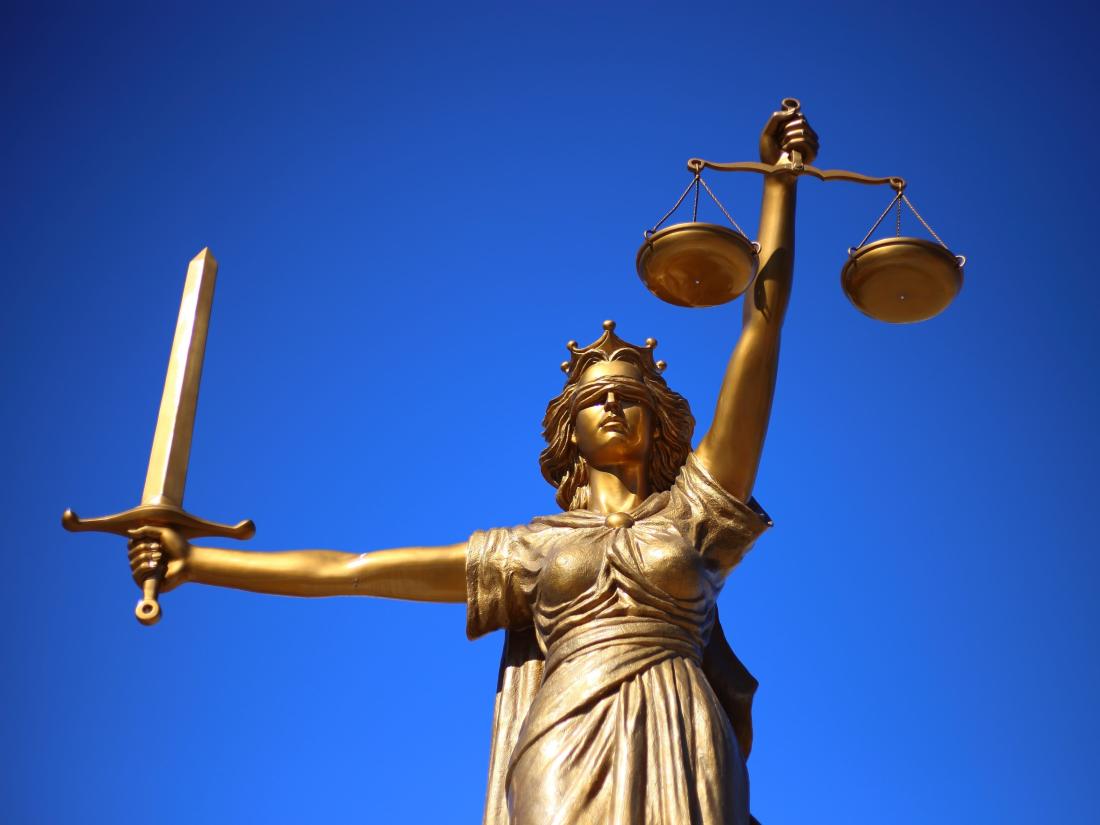 Gold statue of justice with blue background.