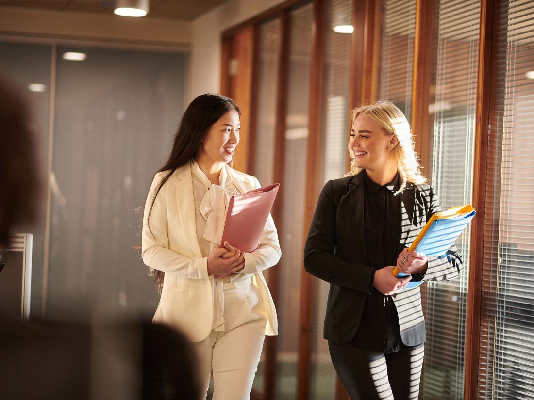 Professional women walking with folders.