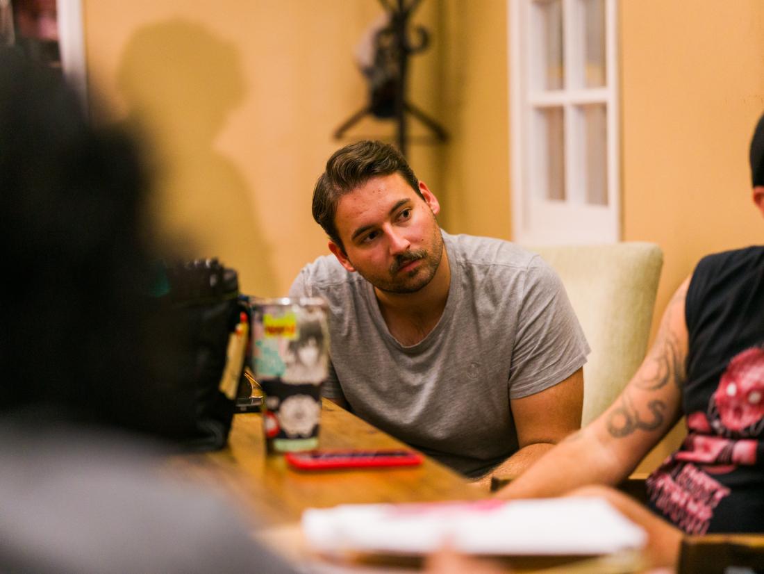 A student works and observes at a table with other students