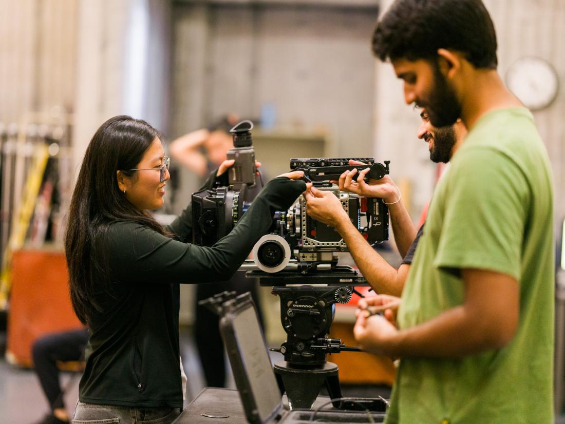 A female student smiles while assembling an Arri Alexa camera