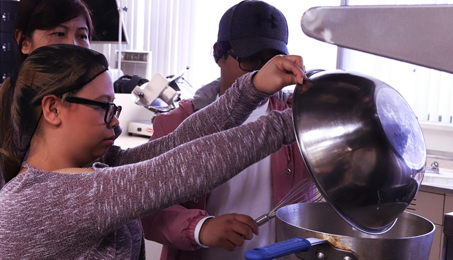 Young People Pouring a Condiment Into a Pan