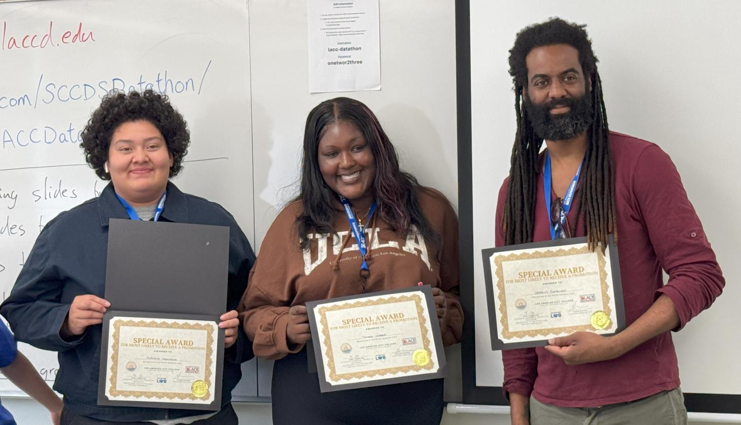 Three students hold their certificates