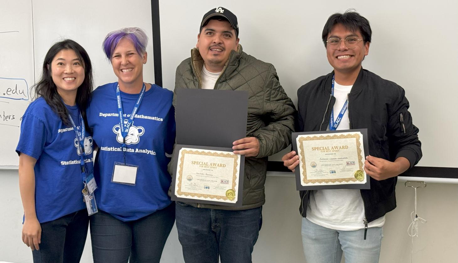 Two faculty members with two students and their certificates