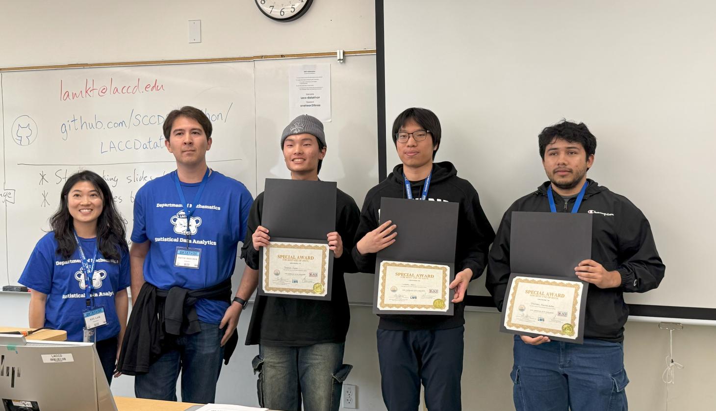 Three students with certificates stand with faculty