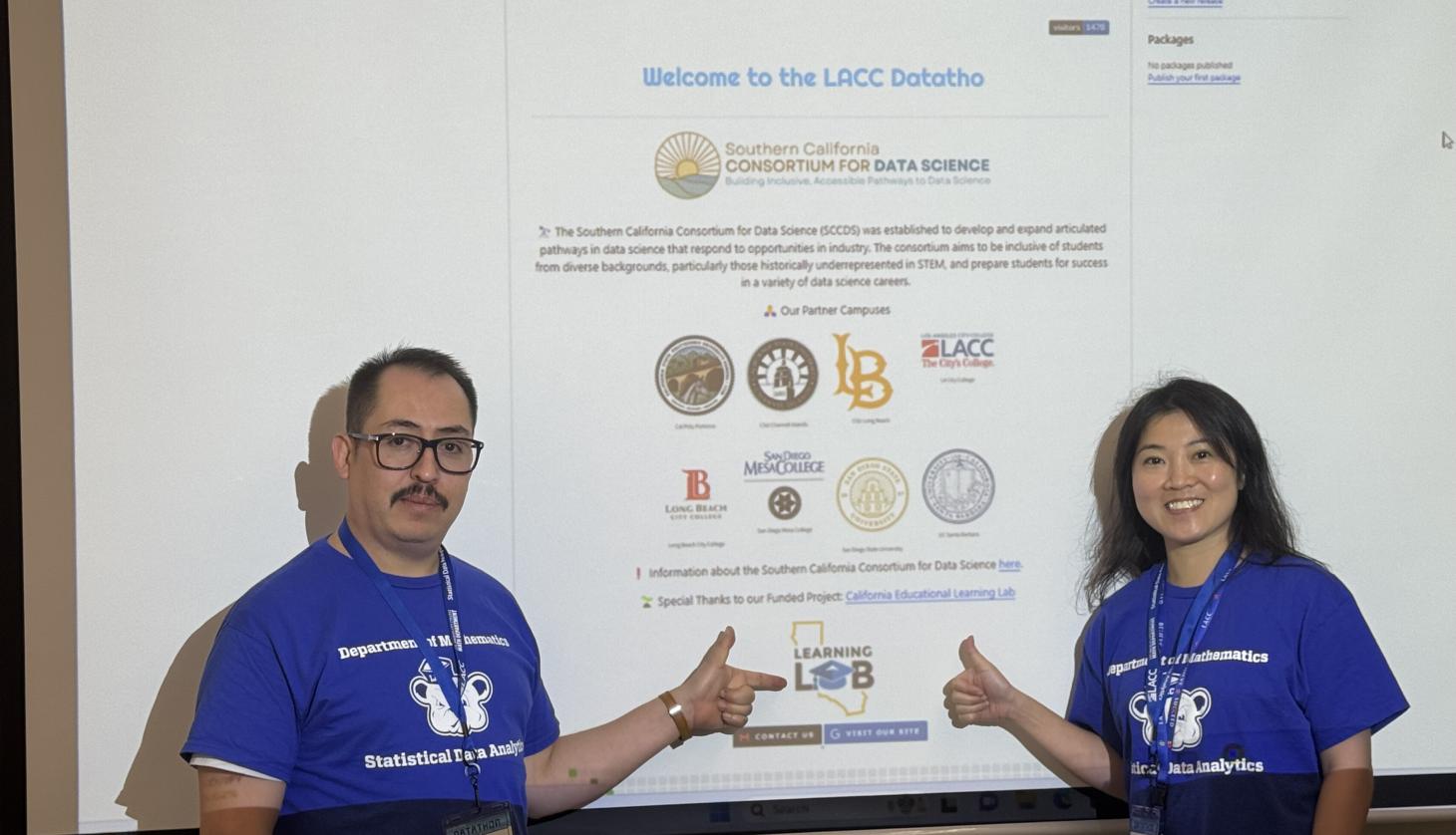 Two faculty members stand in front of welcome powerpoint