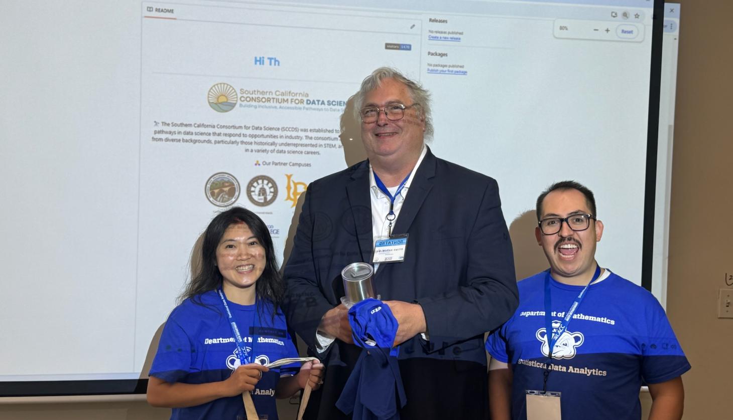 Two faculty members stand with a presenter