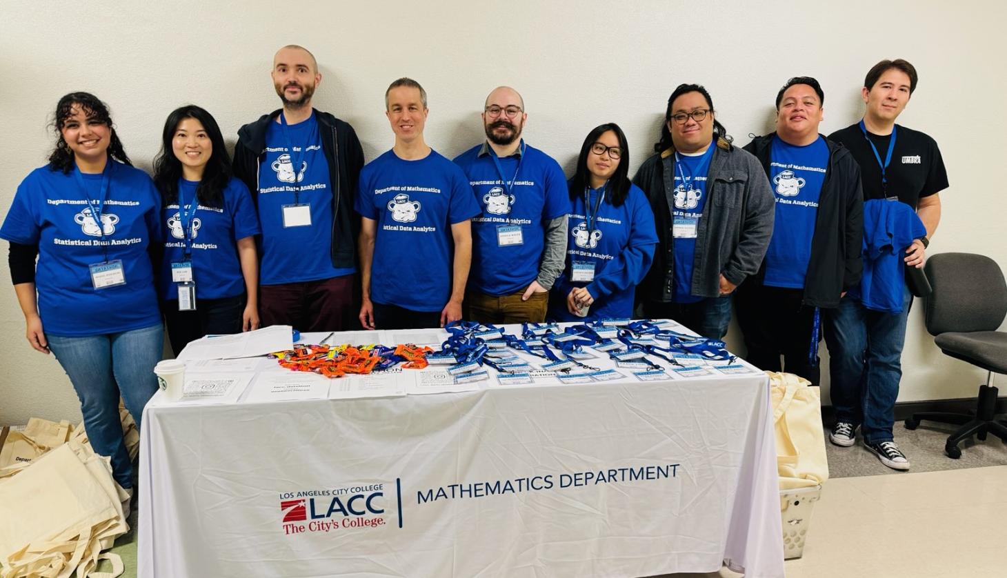Nine faculty members stand behind registration desk