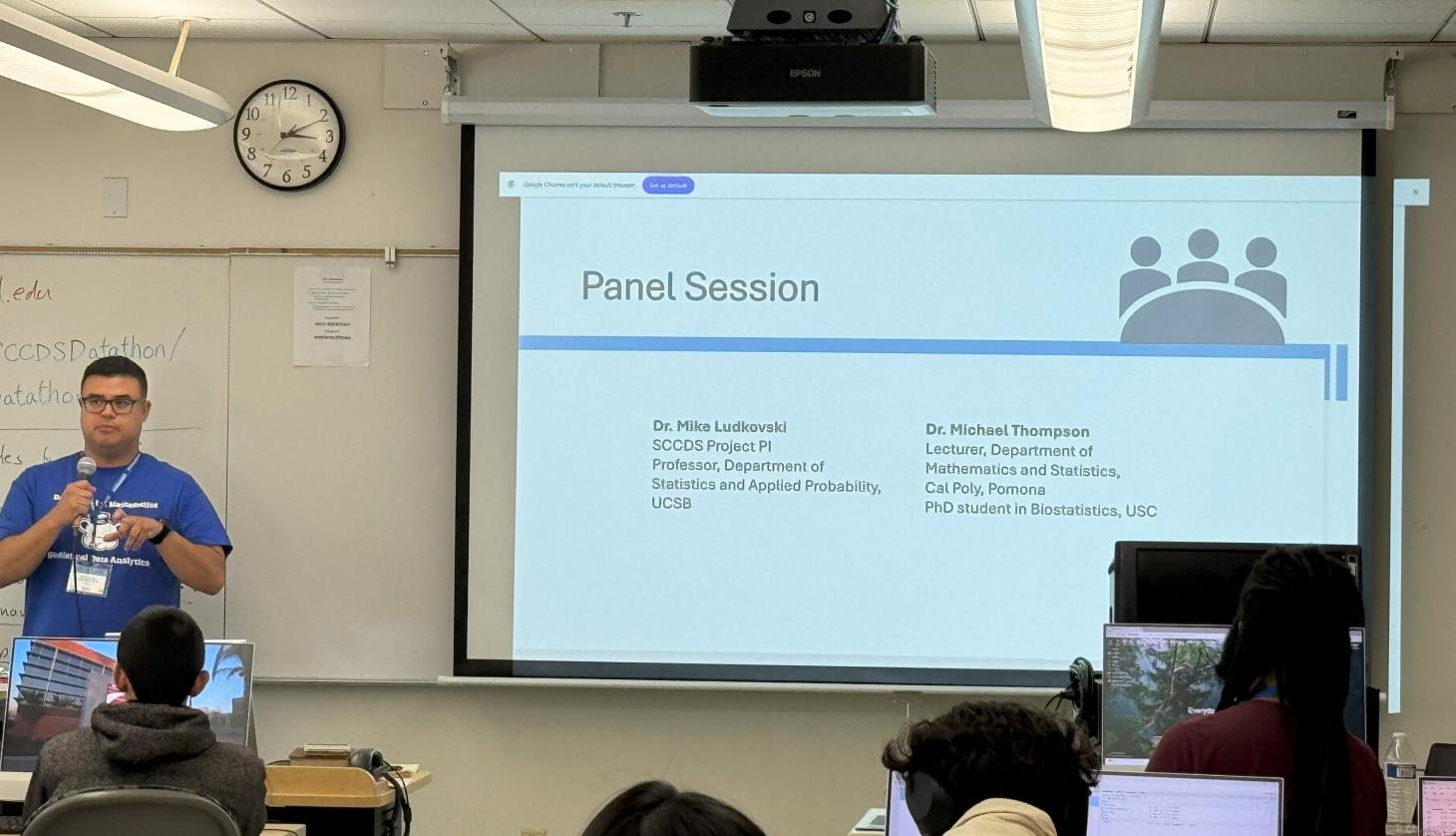 student stands in front of powerpoint presentation