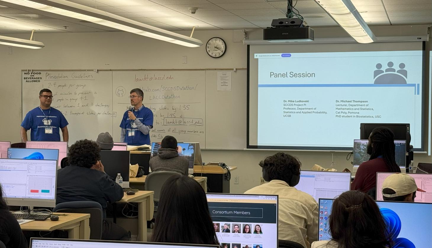 Two students stand in front of powerpoint presentation